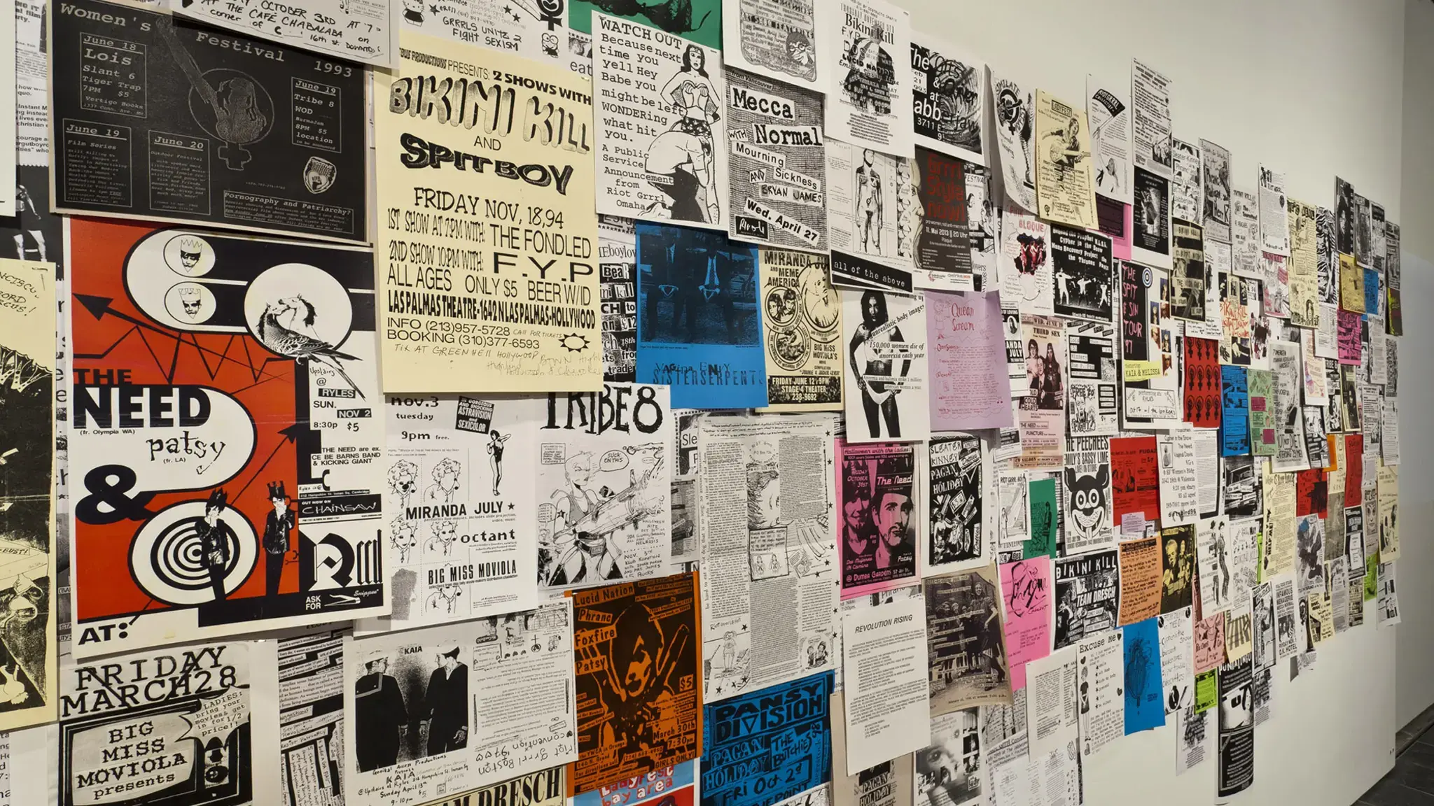 Installation shot of Alien She at the Miller Gallery at Carnegie Mellon University: Posters (c. 1991&ndash;present) from Riot Grrrl related shows, conventions and meetings internationally, solicited from institutional and personal archives through open calls, word-of-mouth, and invitations. Photo courtesy of the Miller Gallery at Carnegie Mellon University.