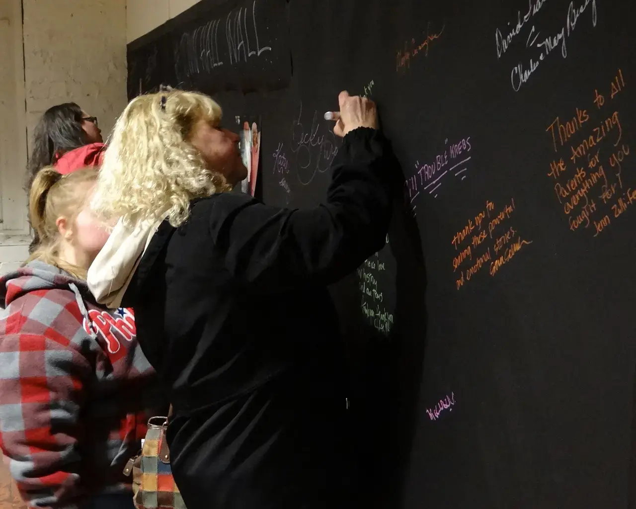 Carol Csaniz signs A Fierce Kind of Love Town Hall Wall. Photo by Christy Beck.