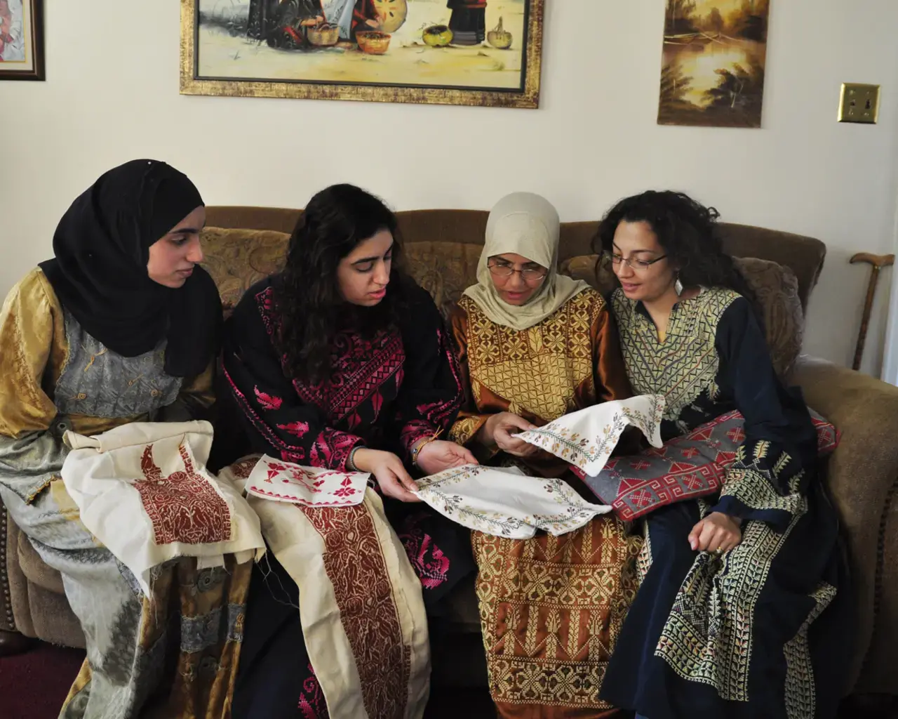 Palestinian needlework (tatreez) artists Wafai Dias, Maisaloon Dias, Alia Sheikh-Yousef, and Nehad Khader look at work. Tatreez patterns from women&rsquo;s home villages, now occupied or destroyed, are assertions of Palestinian history. From the exhibition Tatreez: Needlework of Palestinian women from Philadelphia, curated by Nehad Khader. Photo courtesy of the Philadelphia Folklore Project.