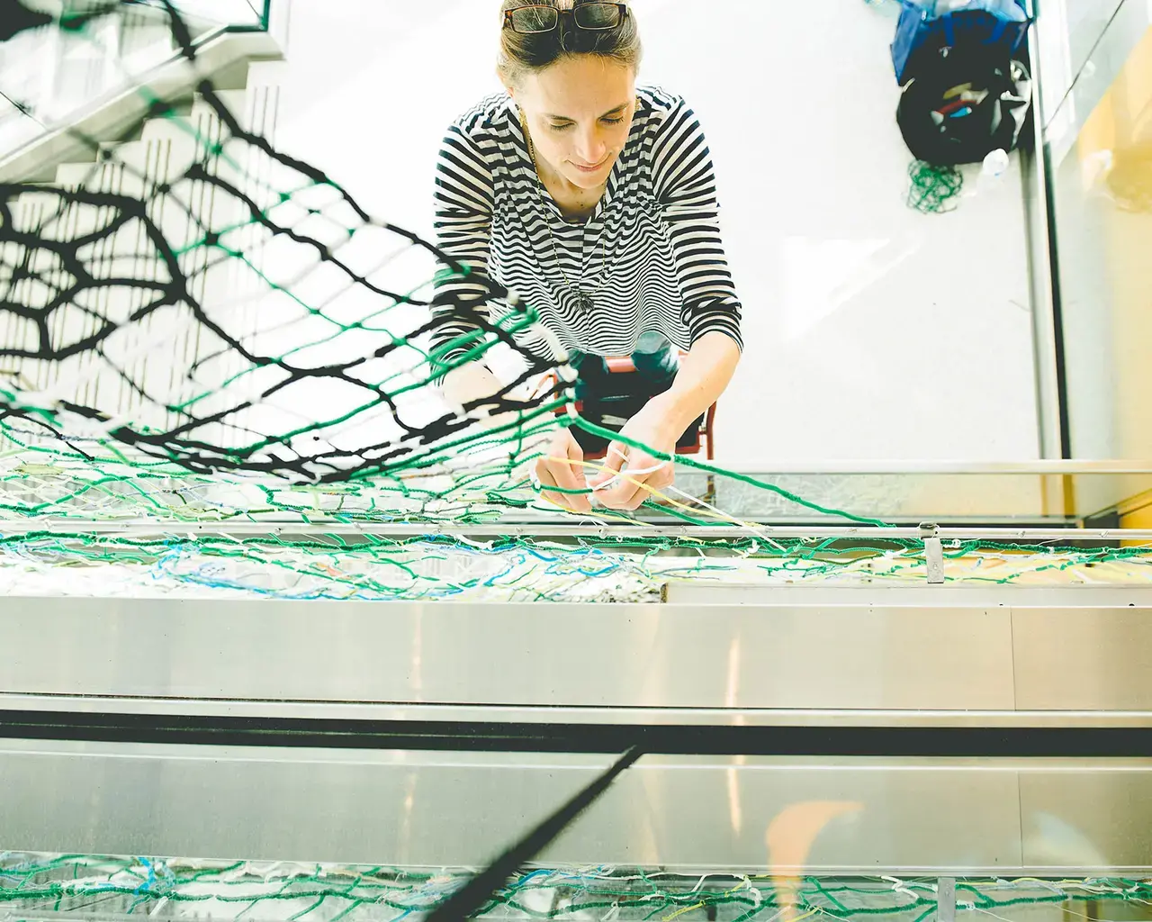 Caroline Lathan-Stiefel working on Quarry, 2015, fabric, plastic, pipe cleaners, wire, thread, fishing weights, steel rods, 80 x 13 feet. Photo by Sarah Alderman.