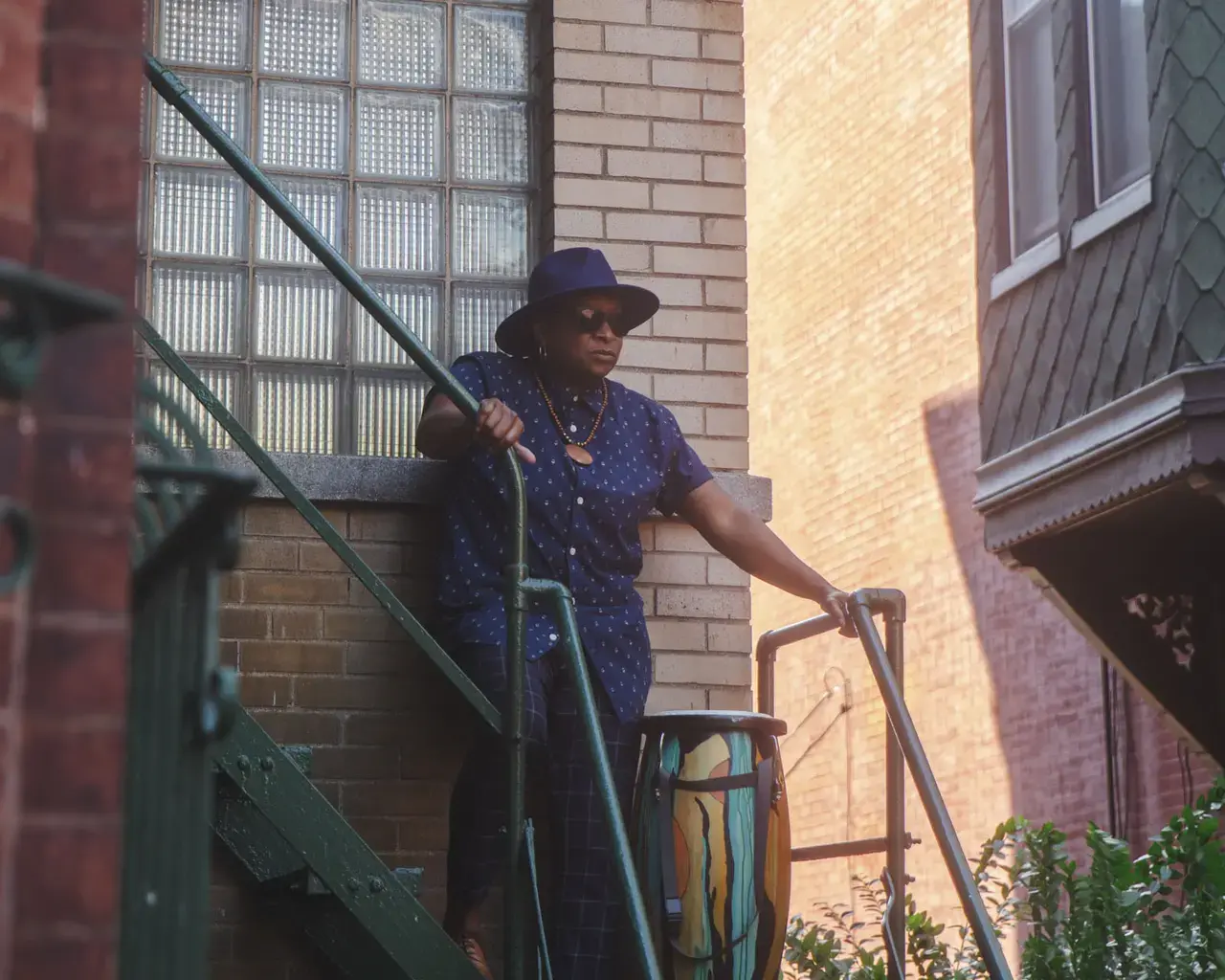 Pew Fellow Karen Smith stands on her fire escape with a drum beside her.