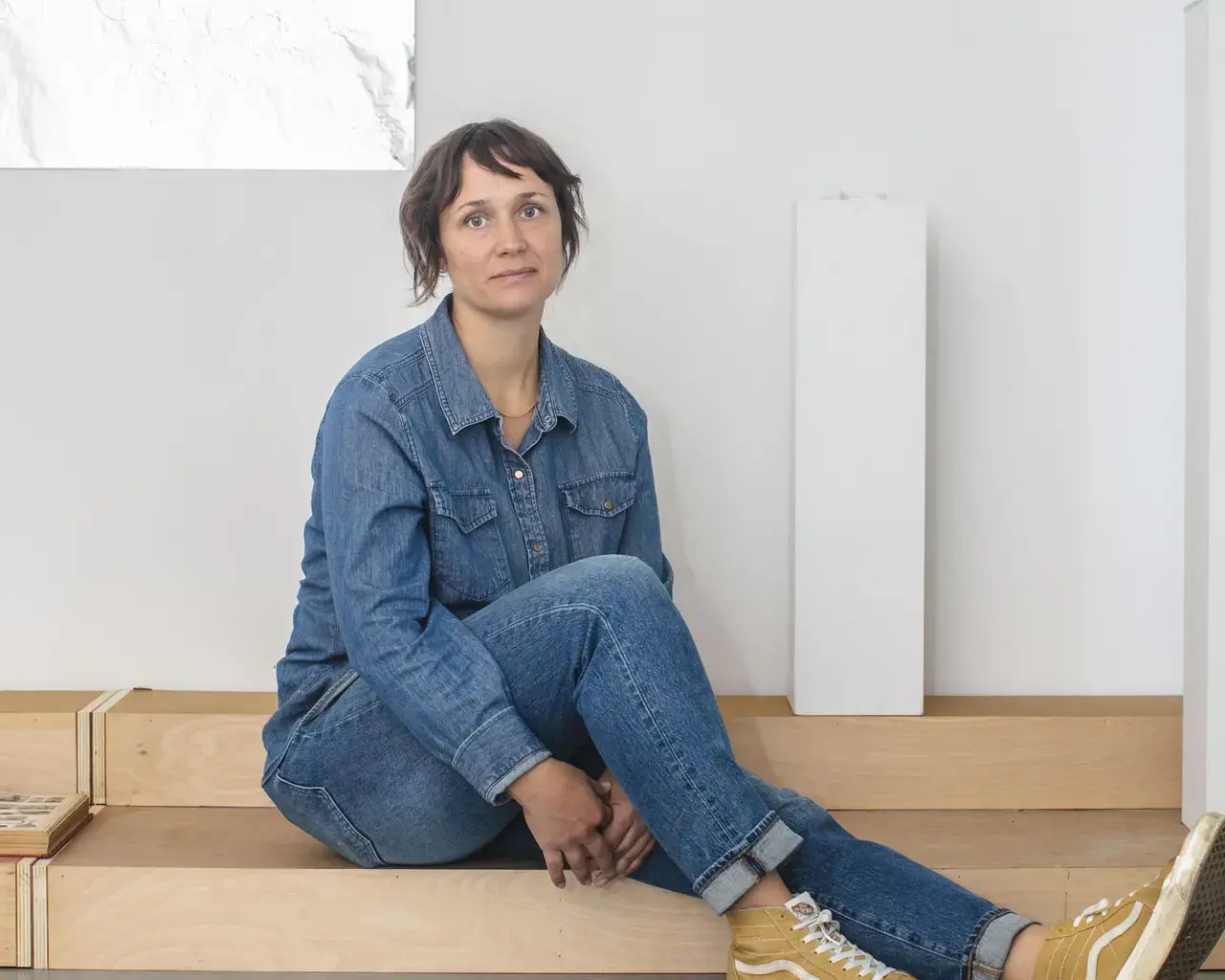A portrait of Pew Fellow Kristin Neville Taylor sitting on a low wooden platform.