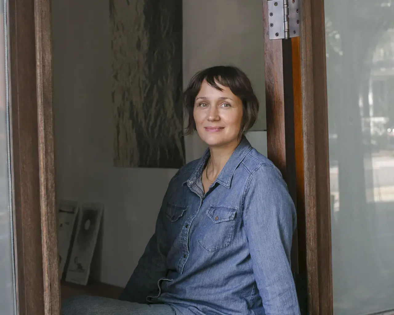 A portrait of Pew Fellow Kristin Neville Taylor sitting in an open window.