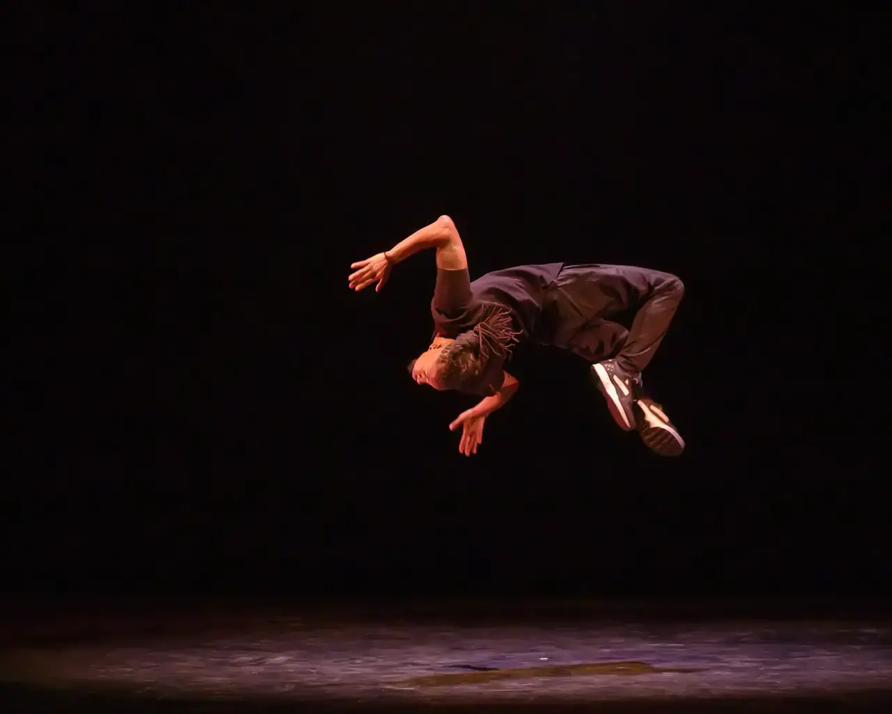 Rennie Harris Puremovement company dancer does a backflip in the air.