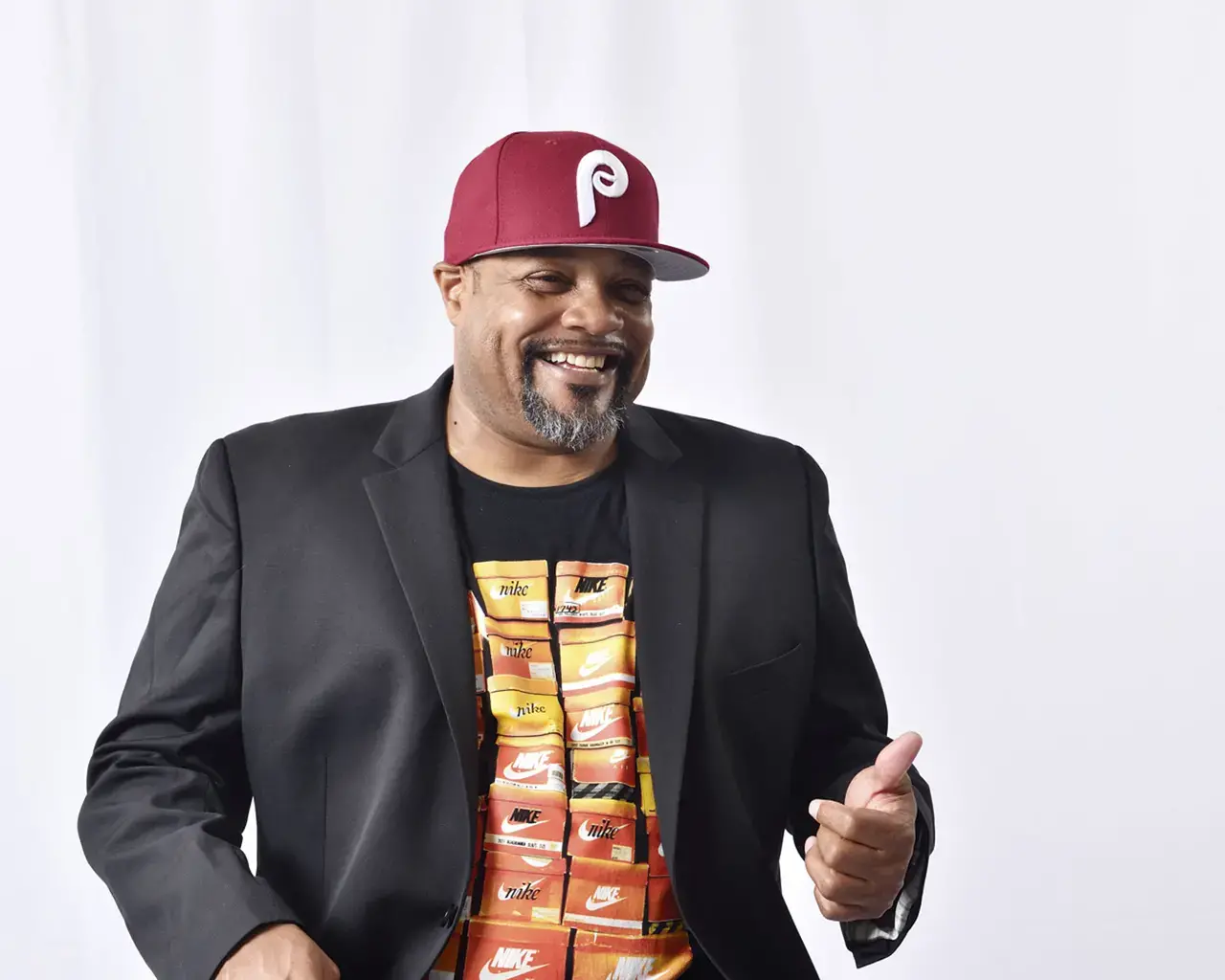 Photo of Rennie Harris wearing a black sports coat, graphic Nike t-shirt, and Phillie's baseball cap.