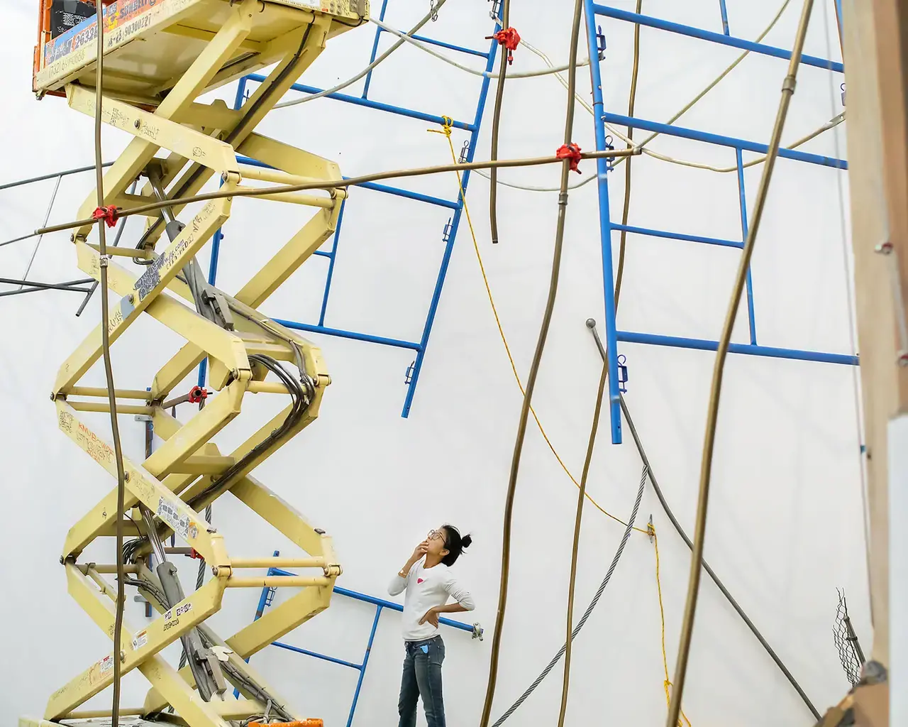 Artist Michelle Lopez with her work "Ballast & Barricades," an installation made of building fragments, pipes, wires, and scaffolding.