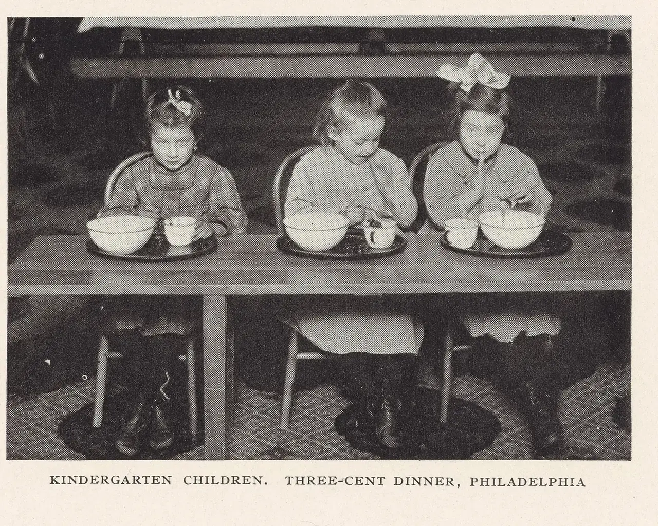 Three girls eating at school, pictured in School Feeding: Its History and Practice at Home and Abroad (1913).