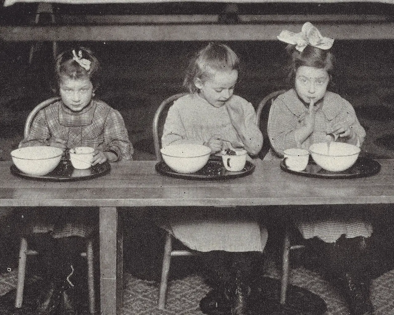 Three girls eating at school, pictured in School Feeding: Its History and Practice at Home and Abroad (1913).