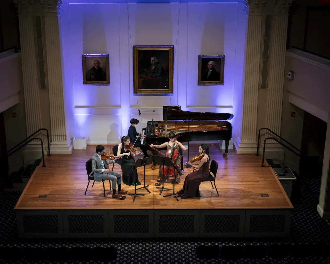 An ensemble of five classical musicans perform on an intimate stage.
