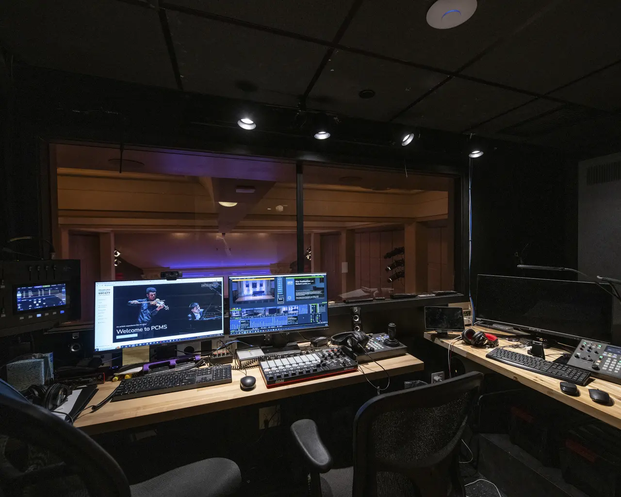 An interior view of the new AV booth at the American Philosophical Society. Multiple monitors are set up in front of a sliding window looking out over the auditorium.