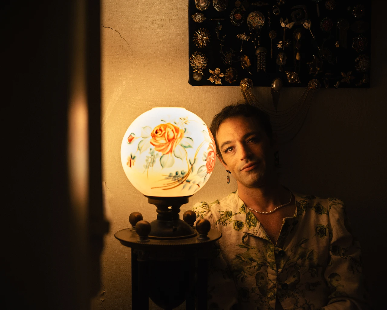 A white woman in a grey button-up top sits by a round glowing lamp.