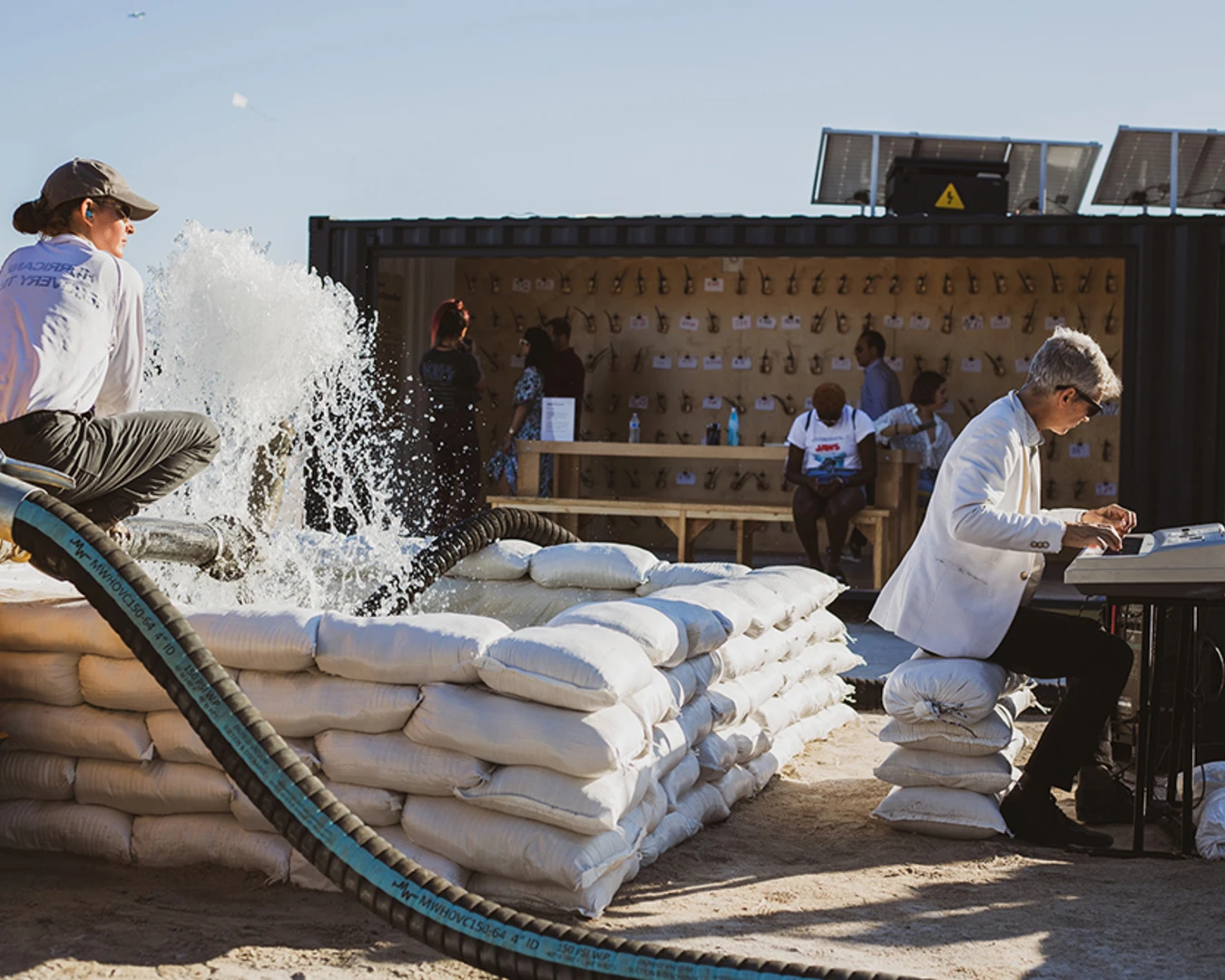 misael soto, Reflecting Pools, 2019. Two performer-operators, one musician, two industrial gas-powered water pumps, approximately 400 filled sandbags, two recycled billboard vinyl tarps, and water. Photo by by Natalia Molina, courtesy of misael soto.&nbsp;