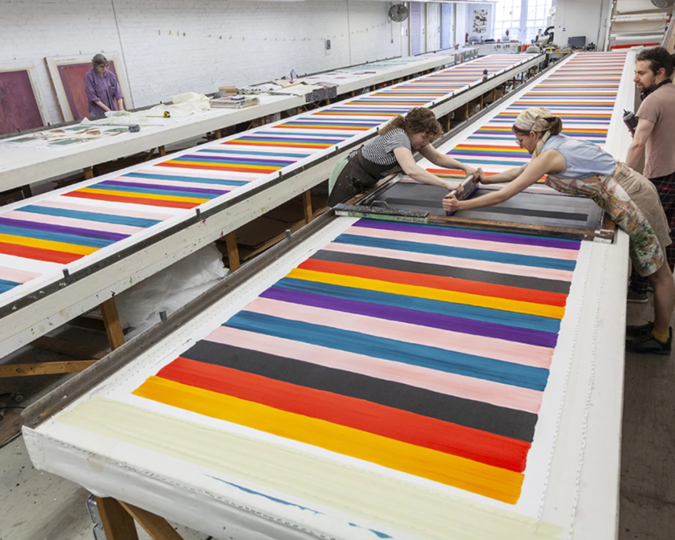 The Fabric Workshop and Museum's Print Project Manager Jill Adler (at right), screenprints Mary Heilmann’s Serape yardage with Studio Assistant Andrea Arts and Senior Project Technician Allen West (at right). Photo by Carlos Avendaño.