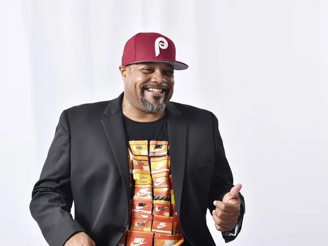 Photo of Rennie Harris wearing a black sports coat, graphic Nike t-shirt, and Phillie's baseball cap.