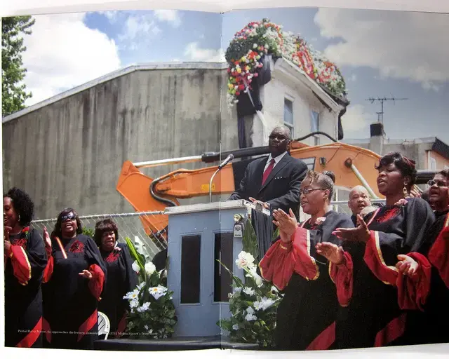 Pastor Harry Moore, Sr. of Mount Olive Baptist Church approaches the lectern remodeled with 3711 Melon Street&rsquo;s front door, as his choir performs at the funeral service for the row home. Interior detail of Temple Contemporary&rsquo;s publication for Funeral for a Home.