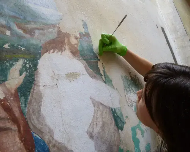 A painting conservator removing residual wax on Peter Receiving the Keys of the Kingdom of Heaven. Courtesy of Eastern State Penitentiary.