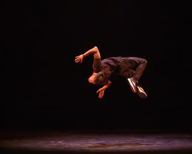 Rennie Harris Puremovement company dancer does a backflip in the air.